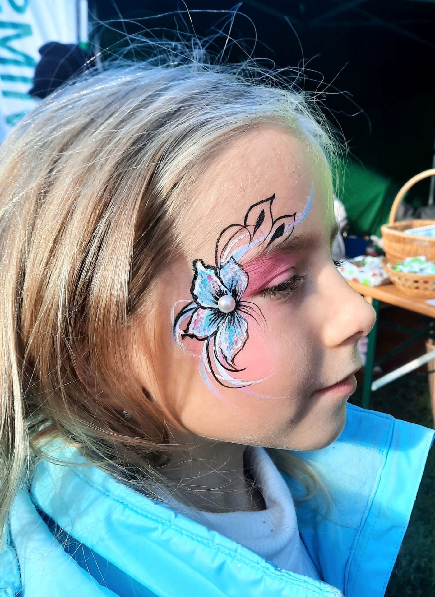 Sinine ja roosa lilleline näomaaling sädelustega